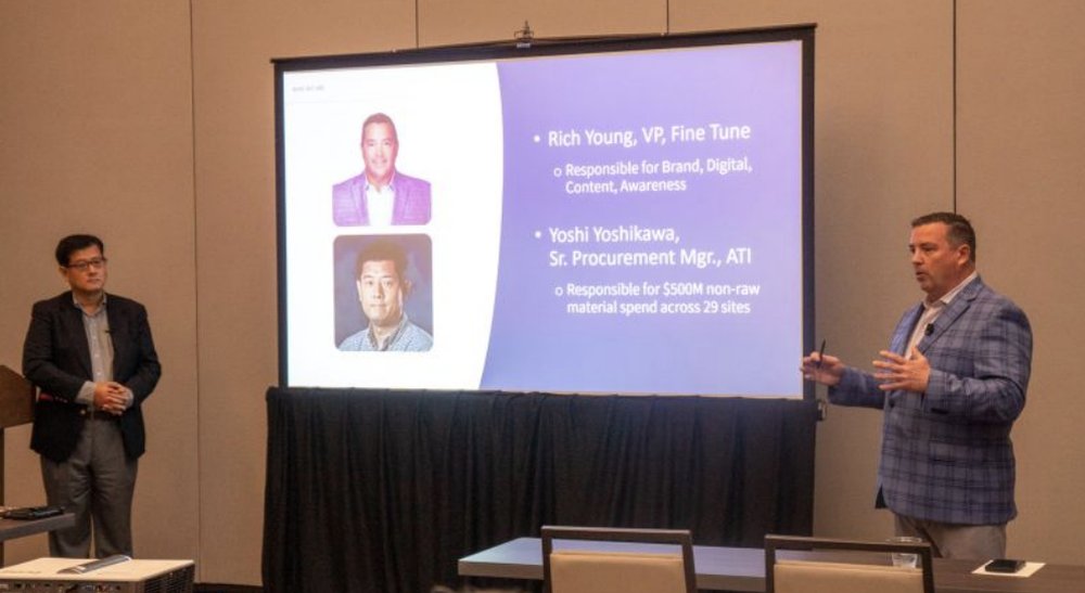 Rich Young presenting on stage at the SIG Global Executive Summit, gesturing toward a screen showing his name and role at Fine Tune next to a co-presenter from ATI.